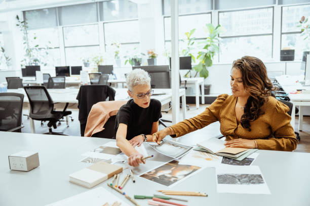 istock Two successful women collaborating at a brightly lit office desk reviewing documents and discussing creative ideas together 2193516660