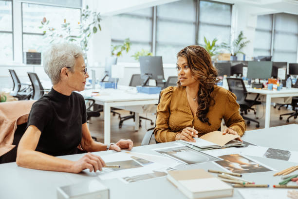 istock Australian women collaborating at a brightly lit office desk reviewing documents and discussing creative ideas together 2193516664