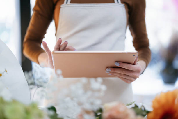 Florist Using Digital Tablet in a Flower Shop Working on Business Tasks