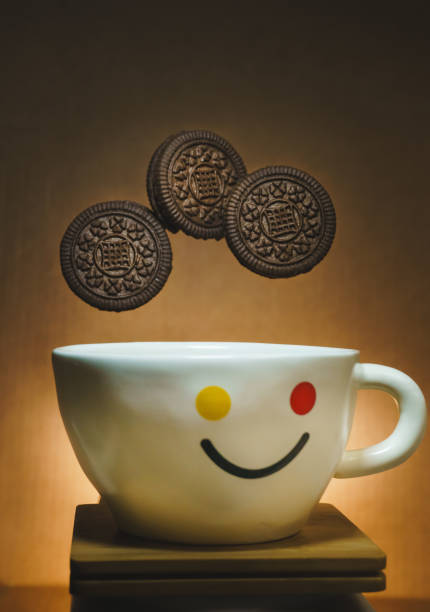 White cup of coffee with smile face on it and flying cookies over it