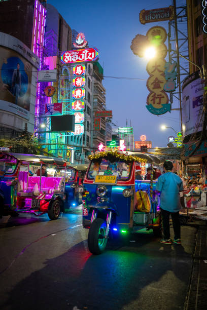 Thailand 24 December 2024 Bangkok: Yaowarat Road, Chinatown at night. The bustling street is illuminated by the lights of shops and restaurants. Classic Tuk Tuk waiting for customers