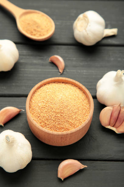 istock Fresh garlic and garlic powder on black wooden background. Using spices for meals. Top view 2193528362