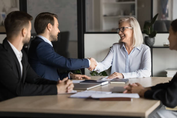istock Mature and young shareholders shaking hands greeting each other 2193529408