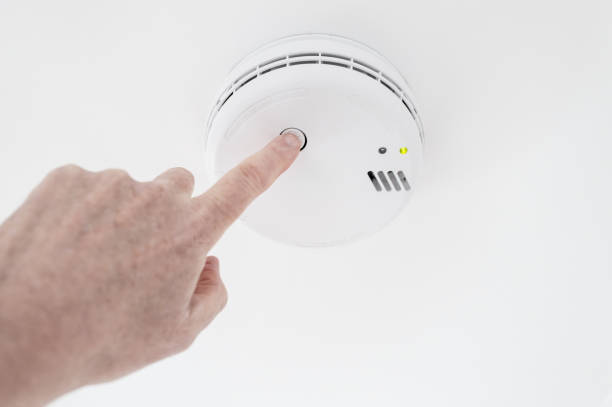 istock Home owner seen performing a weekly test on a ceiling mounted smoke alarm located in the hall of a house. 2193529545