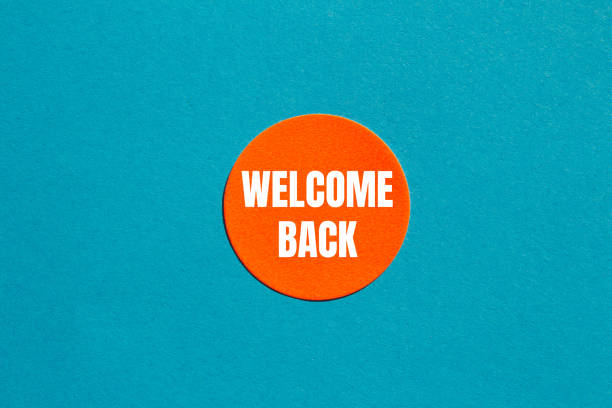 Welcome back message written on round orange sticker with blue background. Conceptual welcome back symbol. Copy space.