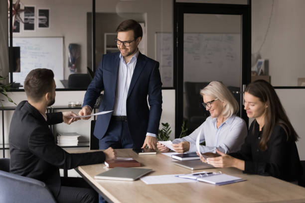 istock Millennial boss giving papers to negotiations members 2193531430
