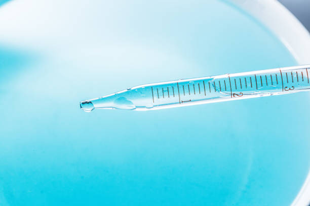 Close-up science experiments,Close up view macro shot of gel with different sized bubbles comes out from lab dropper into petri dish on blue background | Abstract face care gel with hyaluronic acid mixing concept