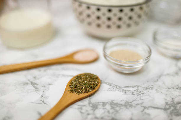 Various ingredients for crafting food including flour, milk, spices, and oil are displayed on a white marble surface, showcasing an arrangement suitable for homemade cooking and baking preparations