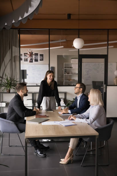 istock Businesspeople laughing, joking seated around table during presentation 2193533160