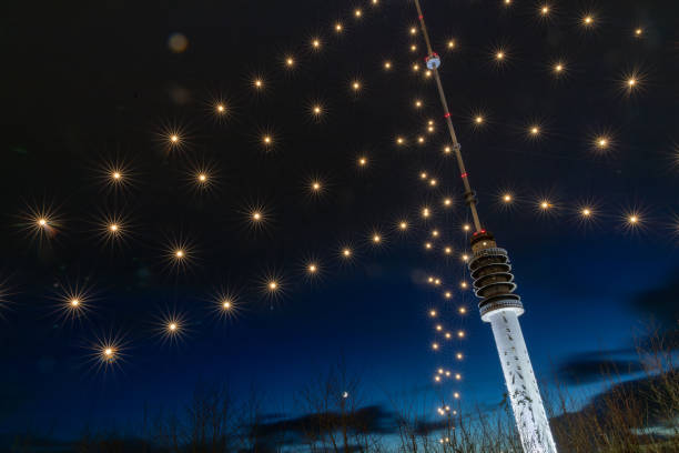 Berlin TV Tower rising above an illuminated Christmas tree at night.