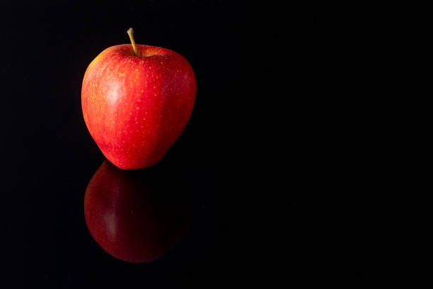 A closeup of juicy red apples on a reflective white surface