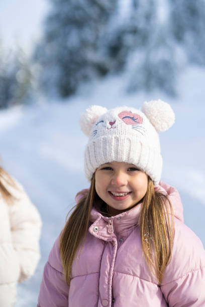 little girl in a pink pom-pom cap playing snowballs in the garden . Selective Focus Cap