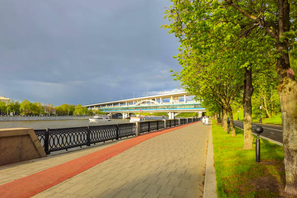 Green walkway along the Moscow River promenade. Pedestrian alley in the green Park of Moscow on the Sparrow hills. Unrecognizable people on a walk.
