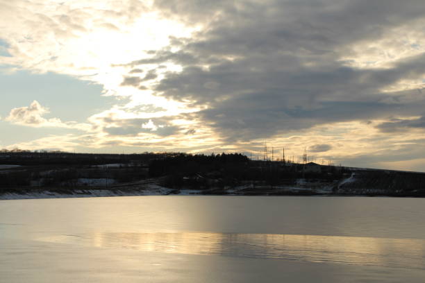 A body of water with a bridge in the background. Outdoor. Water. Sky. Sunset. Beach