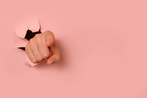 istock Hand pointing through torn pink paper background. Conceptual studio photography with copy space. Design for poster, banner, header, or social media content. 2193546240