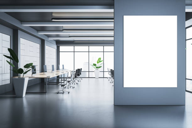 istock Modern office interior with blank poster frame on wall and workstations in open space with large windows and city view. 3D Rendering 2193549410