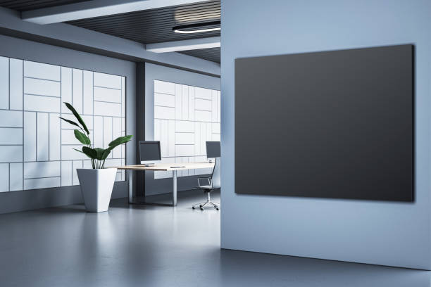 istock Modern empty office interior with blank black frame on wall, desks, plant, and computers in bright workspace environment. 3D Rendering 2193549414