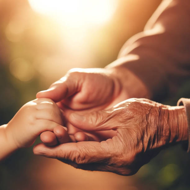 istock An elderly man's hand holds a small child's hand. 2193551702