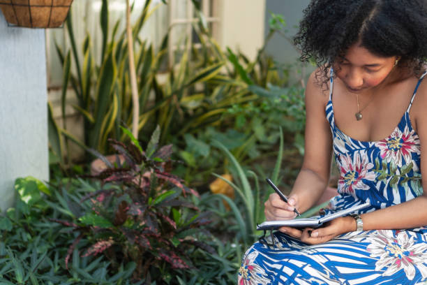 istock Young woman writing in notebook in lush garden setting 2193552906