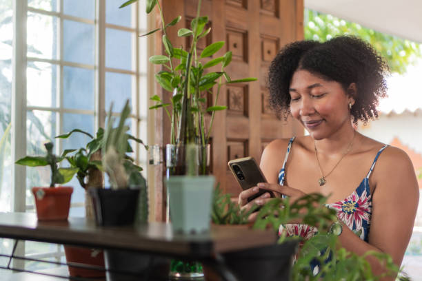 istock Young woman using mobile phone surrounded by plants at home 2193554496