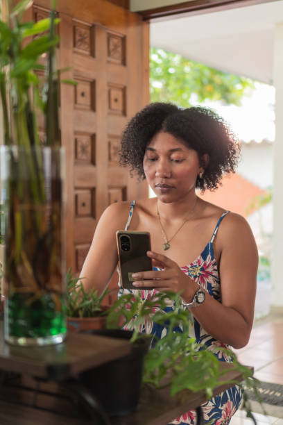 istock Young woman using smartphone at home surrounded by plants 2193554559