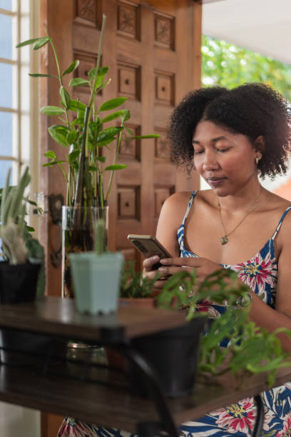 istock Young woman using smartphone at home surrounded by plants 2193554585