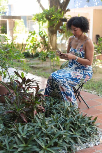 istock Young woman using mobile phone in a lush tropical garden 2193554595