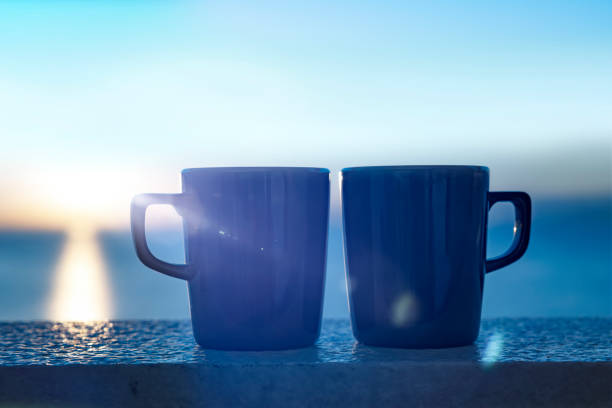 Two coffee cups on a balustrade at sunrise in Greece