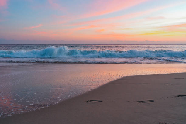 Serene beach scene illuminated by a stunning pink sunset, casting a warm and tranquil glow over the sand and sea