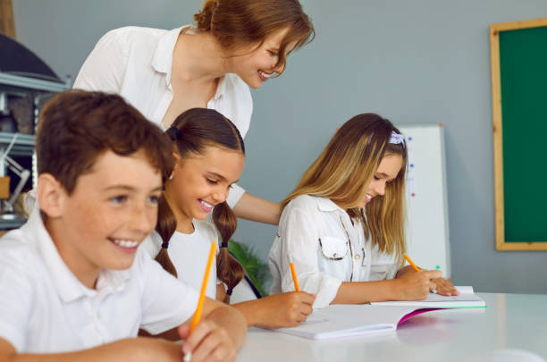 istock Young happy teacher is engaged with students, standing next to student and holding her shoulder approvingly. 2193560858