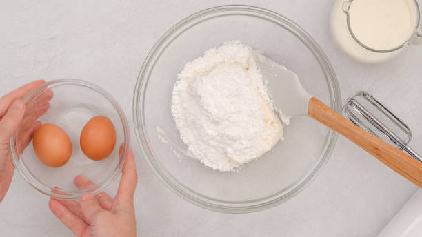 istock Composition of fresh ingredients like cream cheese, eggs, whipped cream, and powdered sugar, a baking process in motion 2193561876