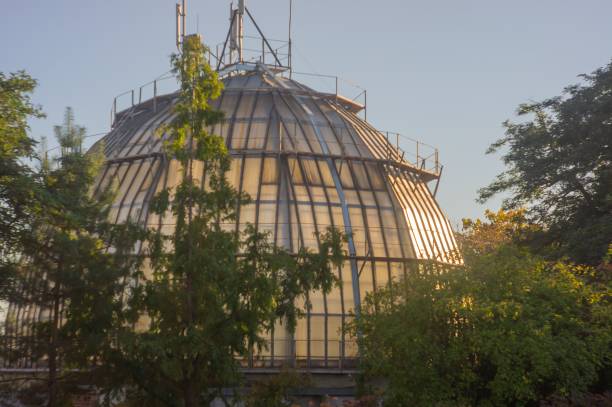 istock Image of a distinctive, translucent or glass-like geodesic dome building with an observation deck, surrounded by leafy trees and set against an overcast sky The building shows no distinguishing mark 2193564654