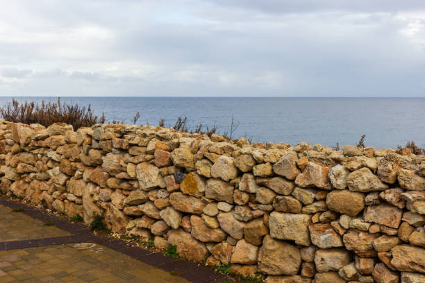 istock Stone Wall Overlooking a Peaceful Coastal Seascape Under a Cloudy Sky 2193565345