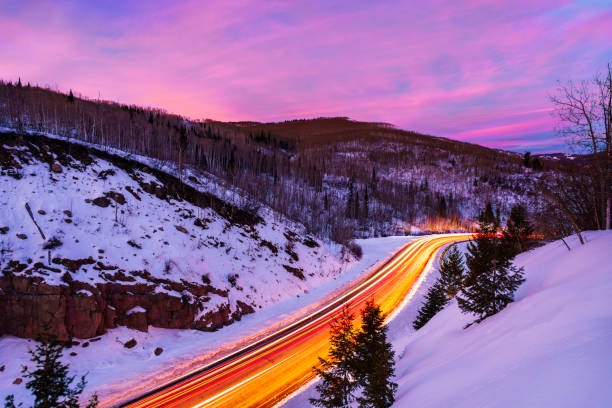 McClure Pass Colorado at Night with Colorful Sky and Light Trails - State Highway 133 going over McClure Pass near Marble and Redstone, Colorado USA. Vehicles driving along road as a colorful sunset with warm colors fill the sky. Scenic view from above.
