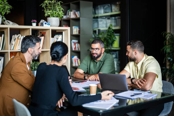 istock Four multiracial business colleagues sitting at table in hybrid work space 2193568102