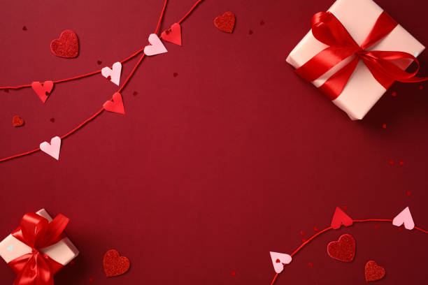 istock Valentine's Day flat lay composition with red and pink hearts garland, gift boxes wrapped with red ribbons, and scattered heart confetti on a red background 2193568836