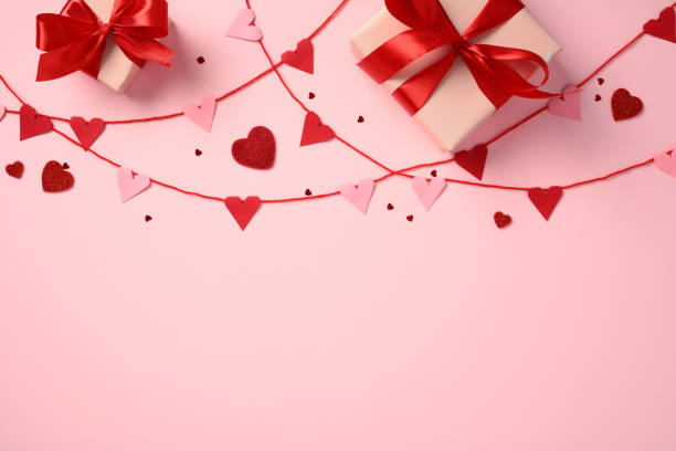 istock Valentine's Day composition. Ribbon bunting with pink and red hearts, gift boxes wrapped with red ribbons, and heart-shaped decorations on a pink background. 2193568954