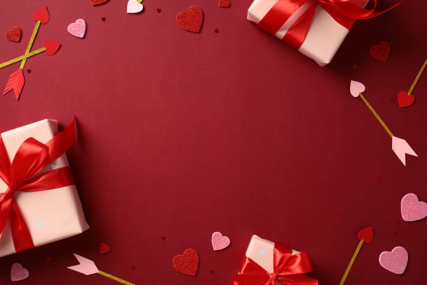 istock Valentine's Day concept. Top view gift boxes with red ribbons, heart-shaped decorations, and Cupid's arrows on a red background 2193568990