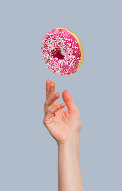 istock Hand with levitation glazed pink donut on blue background. 2193569406