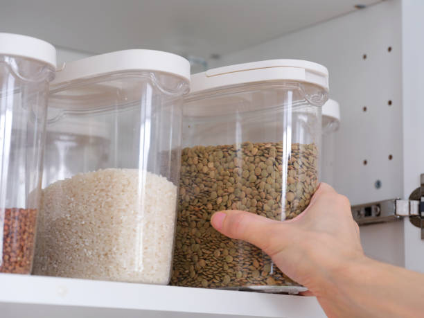 istock A man taking a plastic container of lentils out of a kitchen cabinet. 2193571749