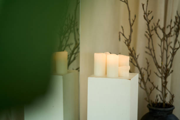 Burning candles on a white plinth create a cozy atmosphere in a room with minimalist decor