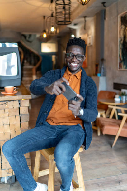 istock Young man playing video games on smartphone at coffee 2193576055