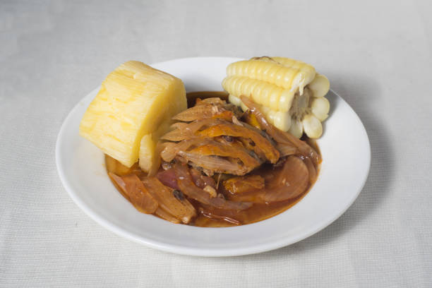 Peruvian escabeche dish with cassava and corn on a white plate