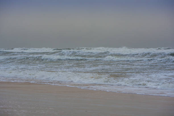 Horizontal color photo of a stormy surf on the shore of the Baltic Sea on a cloudy January day.