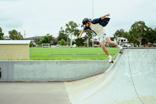 istock Young skateboarder wearing a helmet practicing tricks on a half-pipe in an outdoor skate park on a cloudy day 2193578883