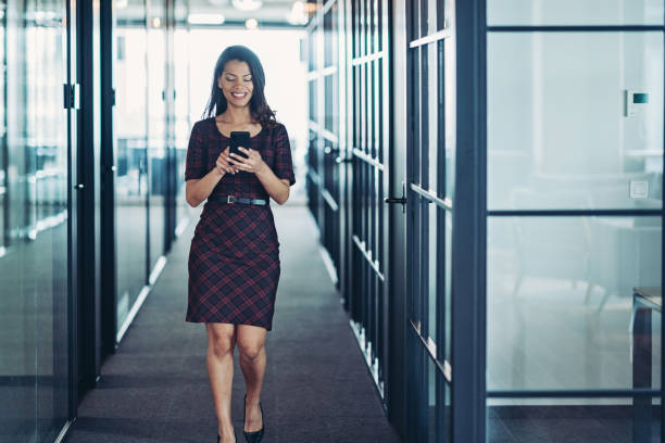 istock Young woman walking and texting in a modern office space 2193579553