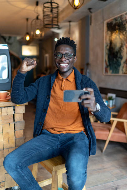 istock Happy young man using phone and celebrating while enjoying in cafe. 2193580085