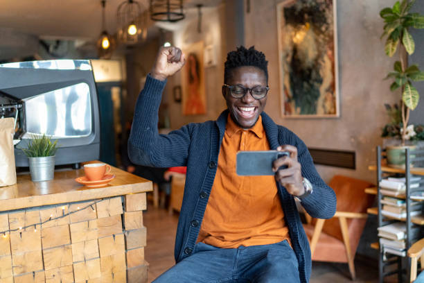 istock Happy young man using phone and celebrating while enjoying in cafe. 2193580167