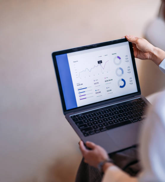 istock Close-Up of Hands Holding a Laptop Displaying Business Analytics Charts 2193580235