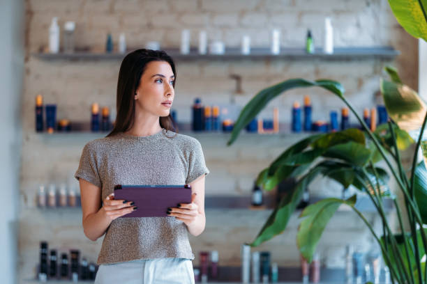 Woman Holding Tablet in Modern Shop with Natural Greenery